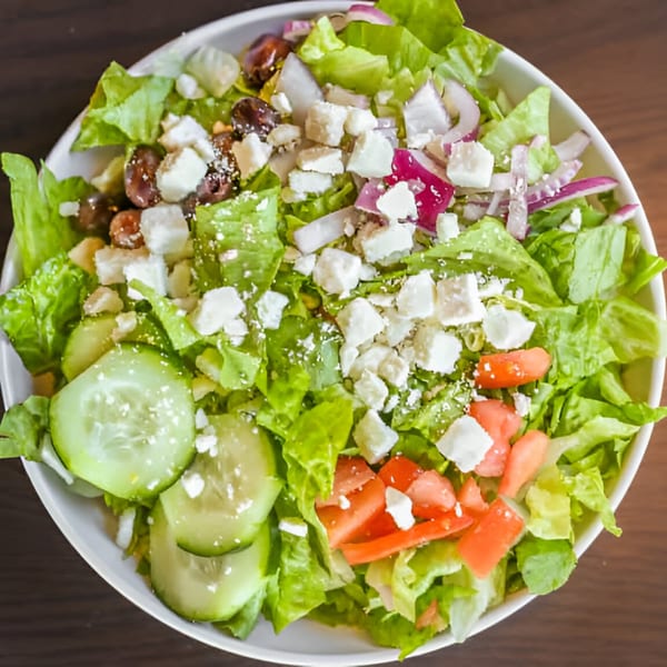 Fresh garden salad with lettuce, cucumbers, tomatoes, red onions, olives, and feta cheese.